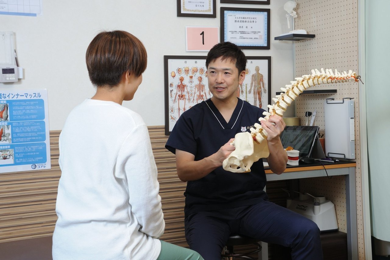 模型を使って腰痛の原因を丁寧に説明している院長、奥原敬の画像