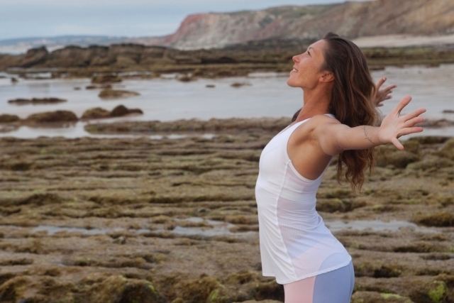 海岸で両手を広げている健康的な女性のイメージ