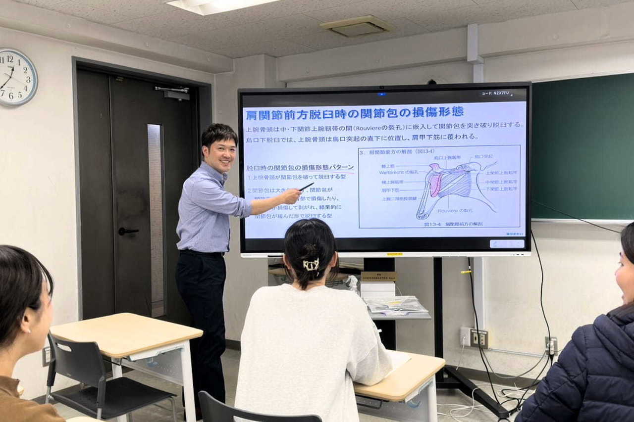 柔道整復師を目指す学生に向けて専門学校で授業を行う院長の様子。教員免許を持つ柔道整復師として将来の施術者を指導している風景
