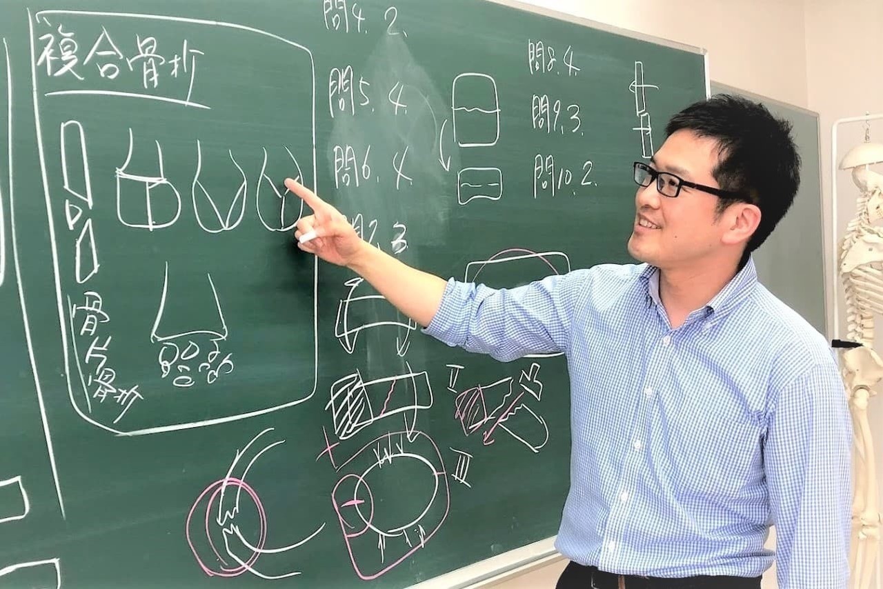 黒板を使って他の施術者に技術指導を行う院長の様子。猫背改善メソッドや動きの改善に関する講義風景